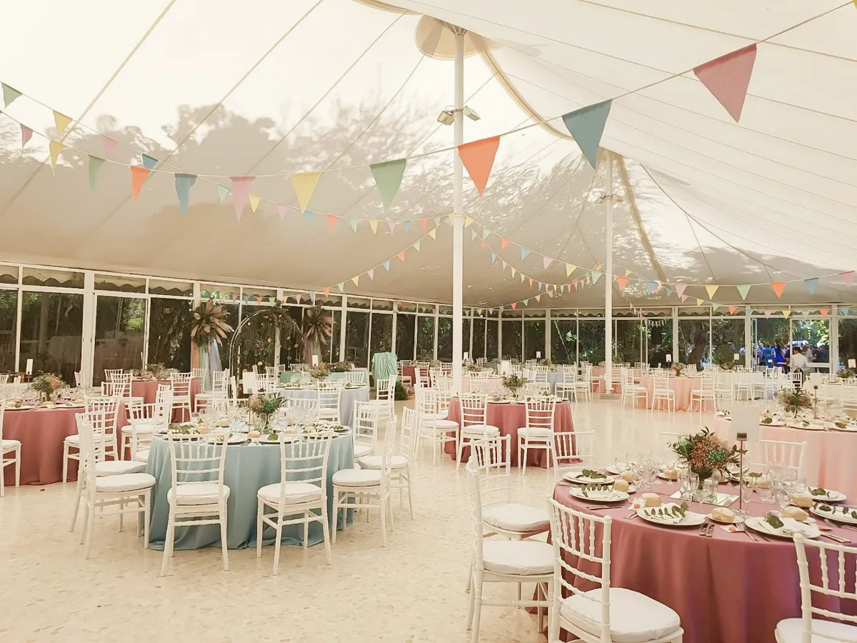 Carpa decorada con banderines de colores y mesas en tonos pastel