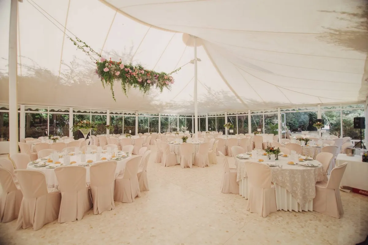Carpa translúcida montada con mesas redondas vestidas de blanco